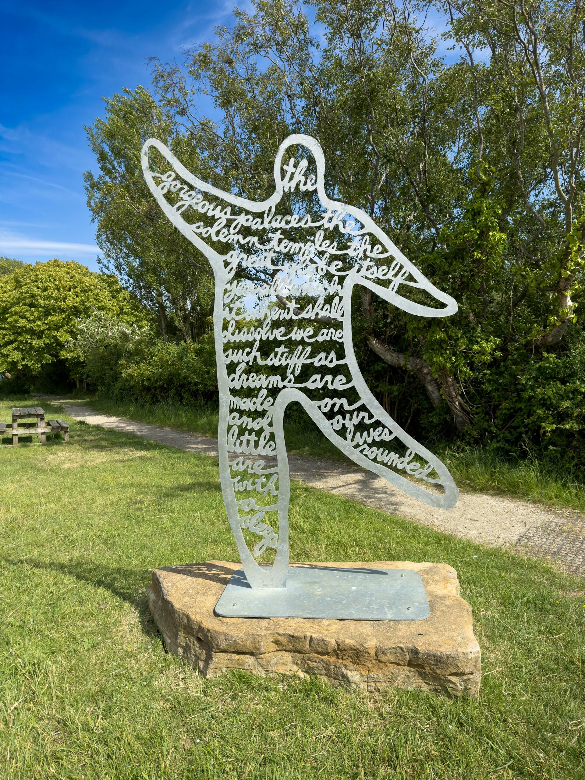 a metal sculpture with cut-out words to make a poem in the shape of a person