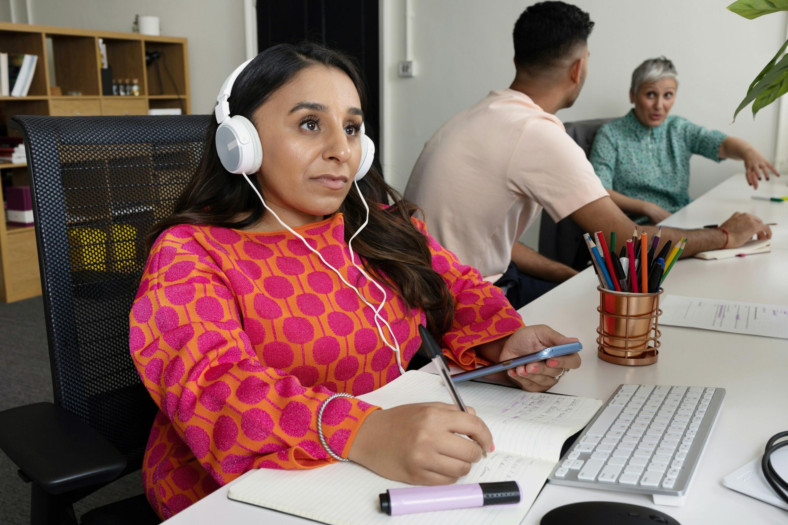 A student studying on the computer and writing in a notebook.
