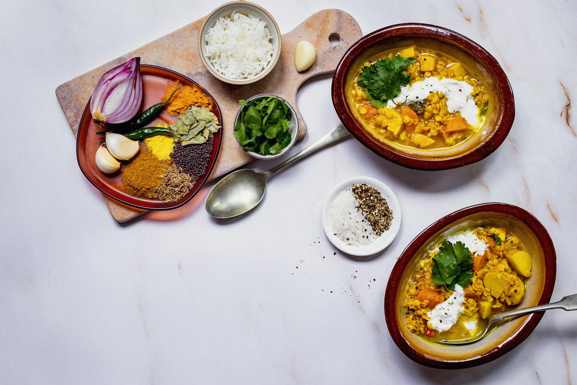 Two Indian dishes with spices on a cutting board.