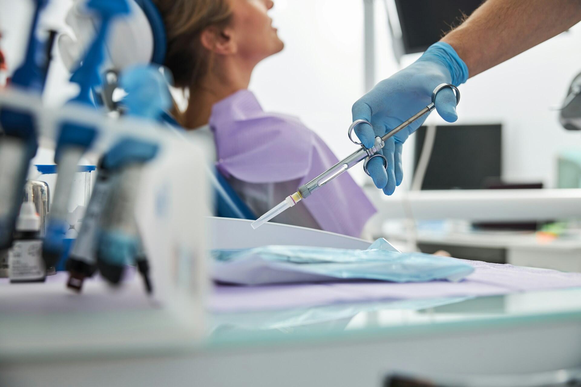 A dentist preparing anaesthetic for a patient.