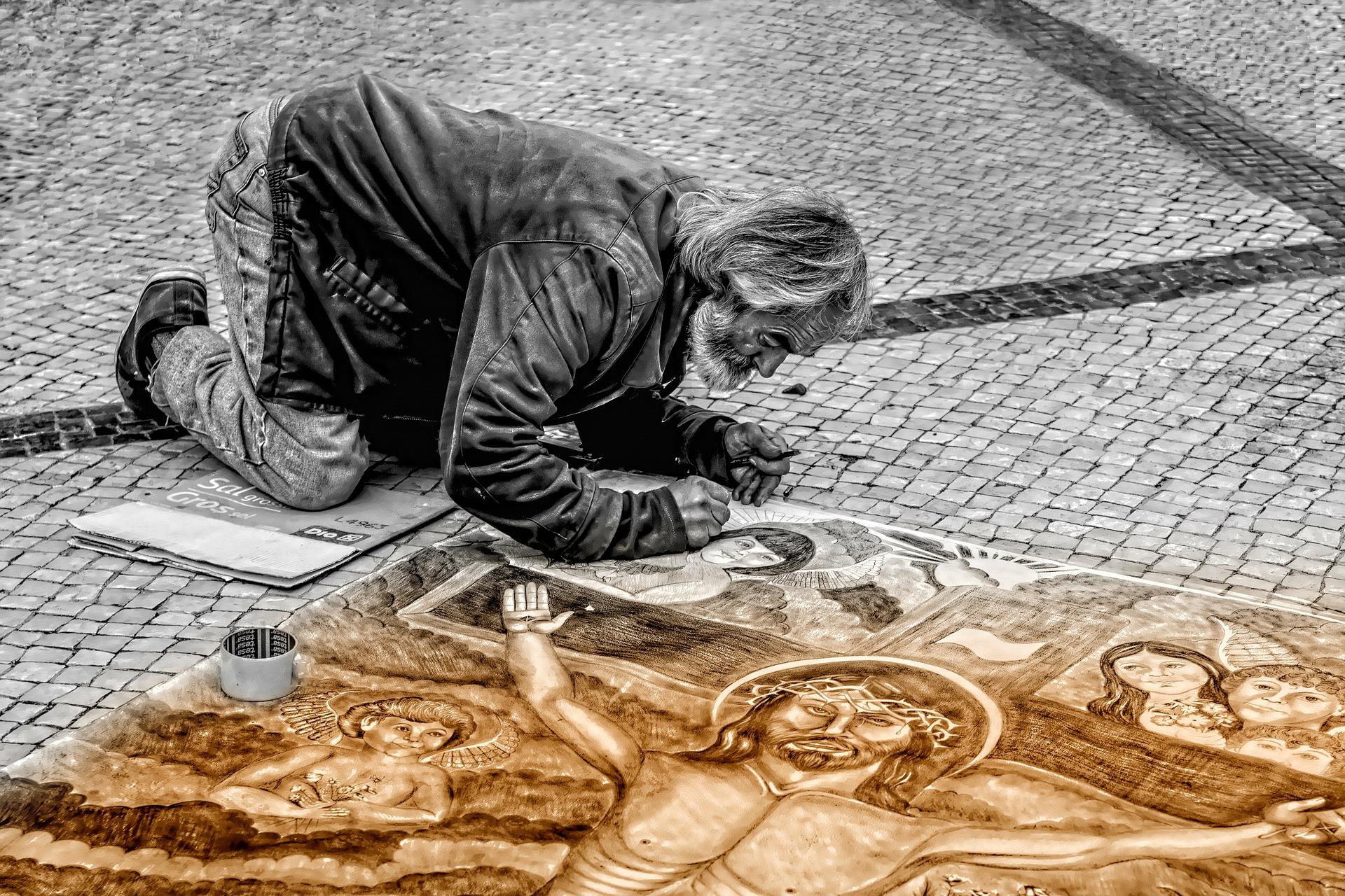 A man working on his street art, creating a religious mural 