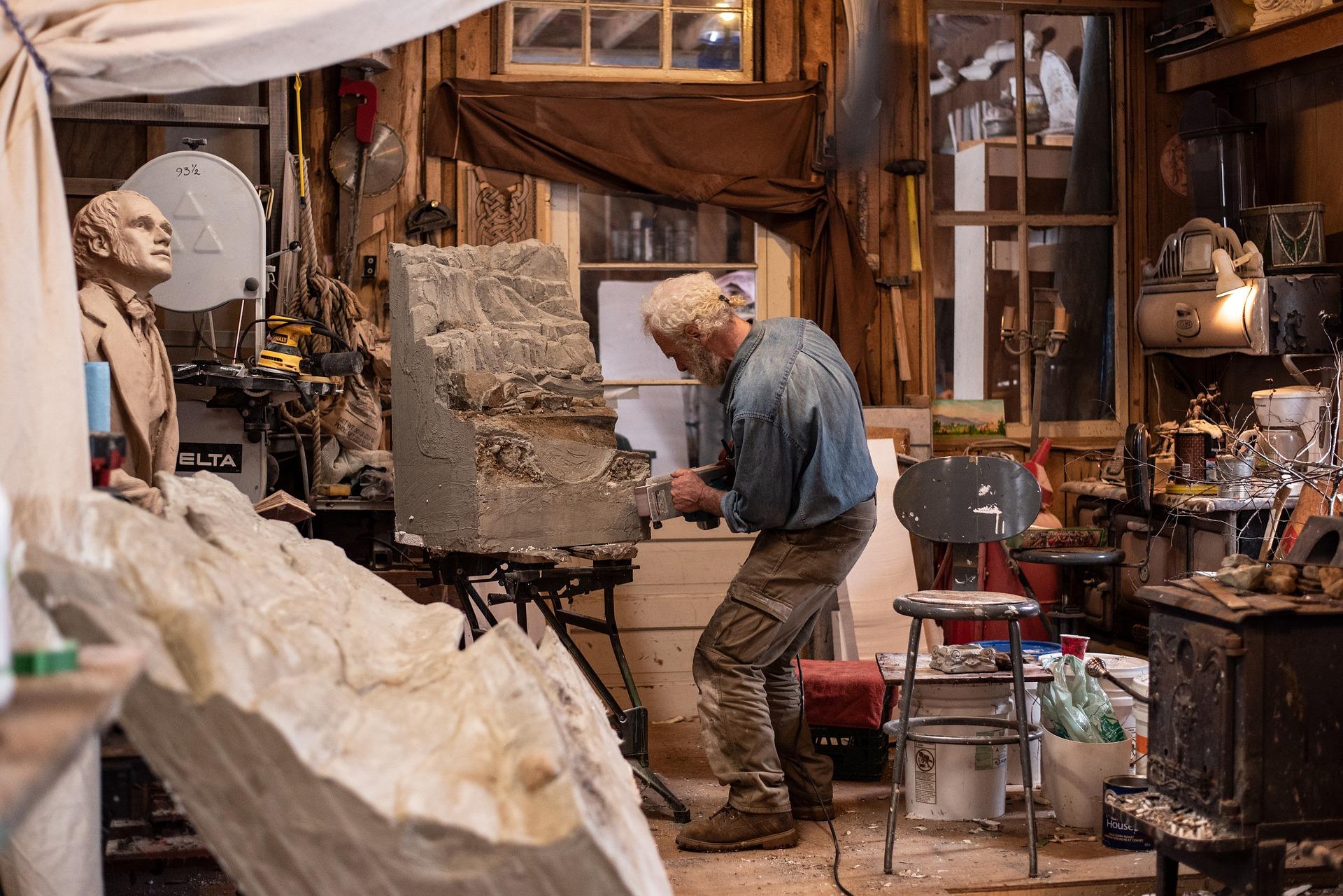 A man with white hair working on a sculpture