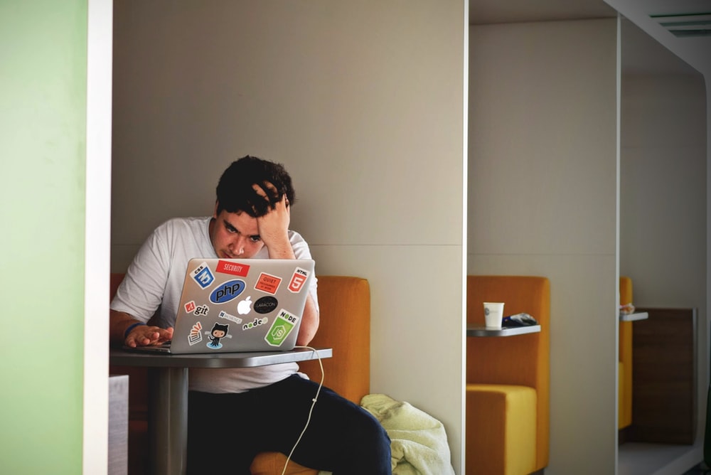 A student scratching his head with frustration while sitting in a cafeteria