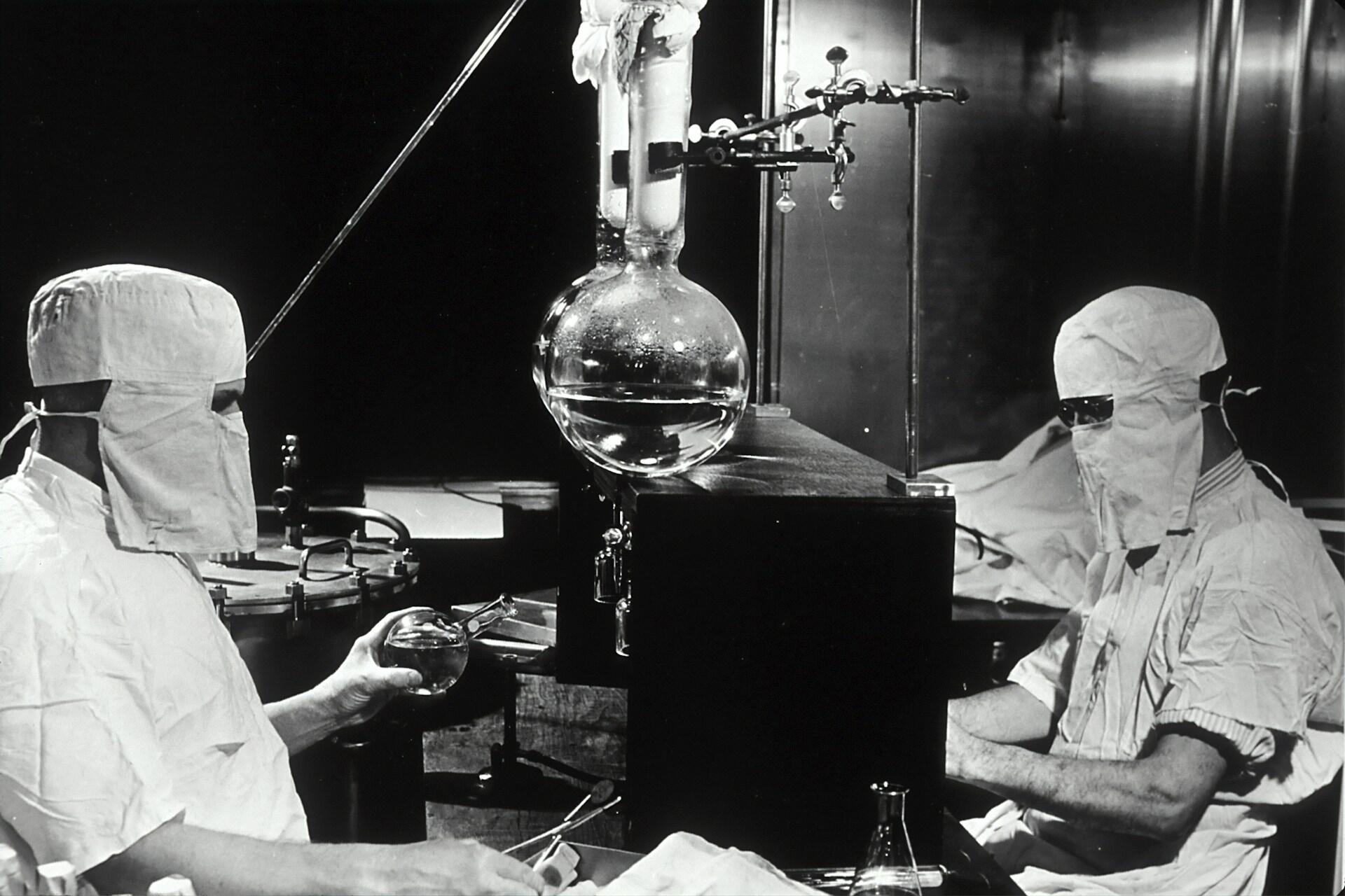 Two scientists wearing protective gear while working with radiation.