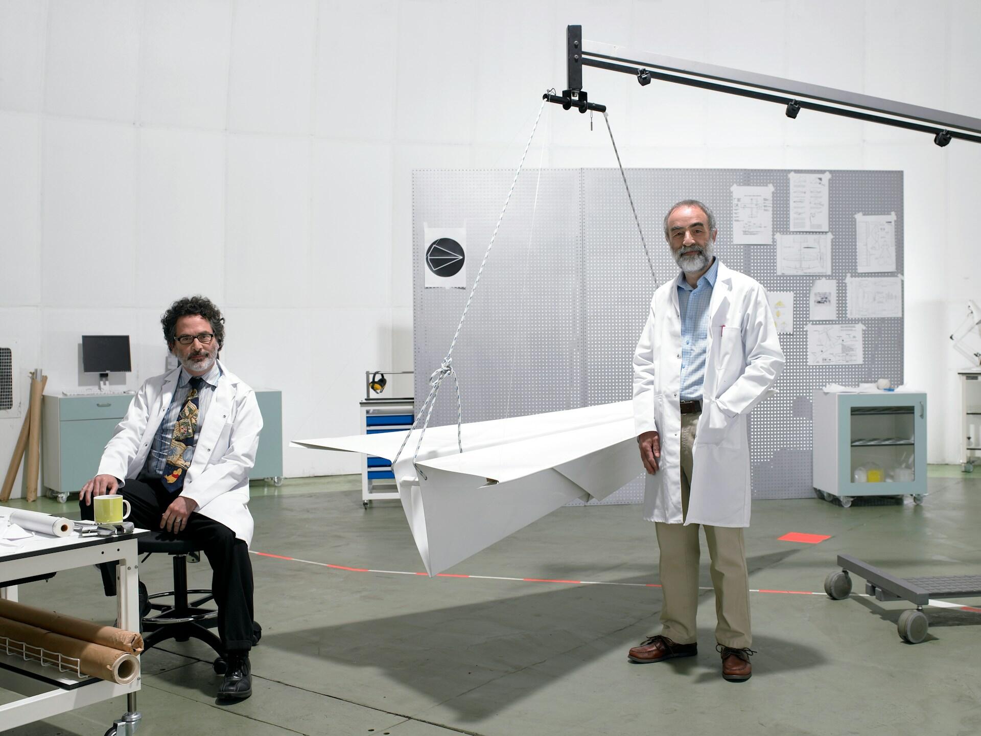 Two physicists next to a giant paper airplane.