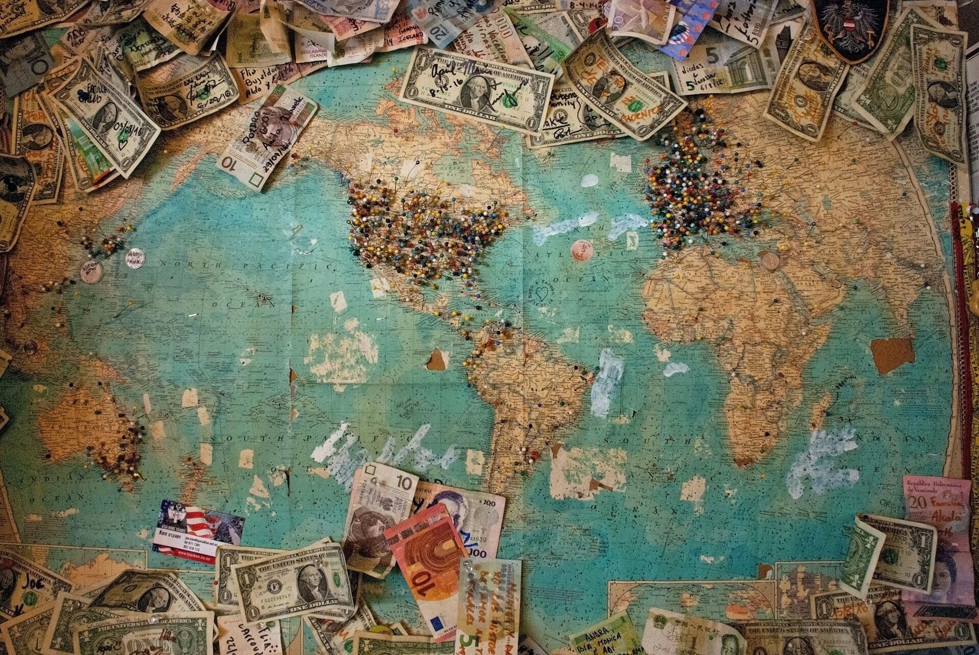 A world map with pins and money by it.