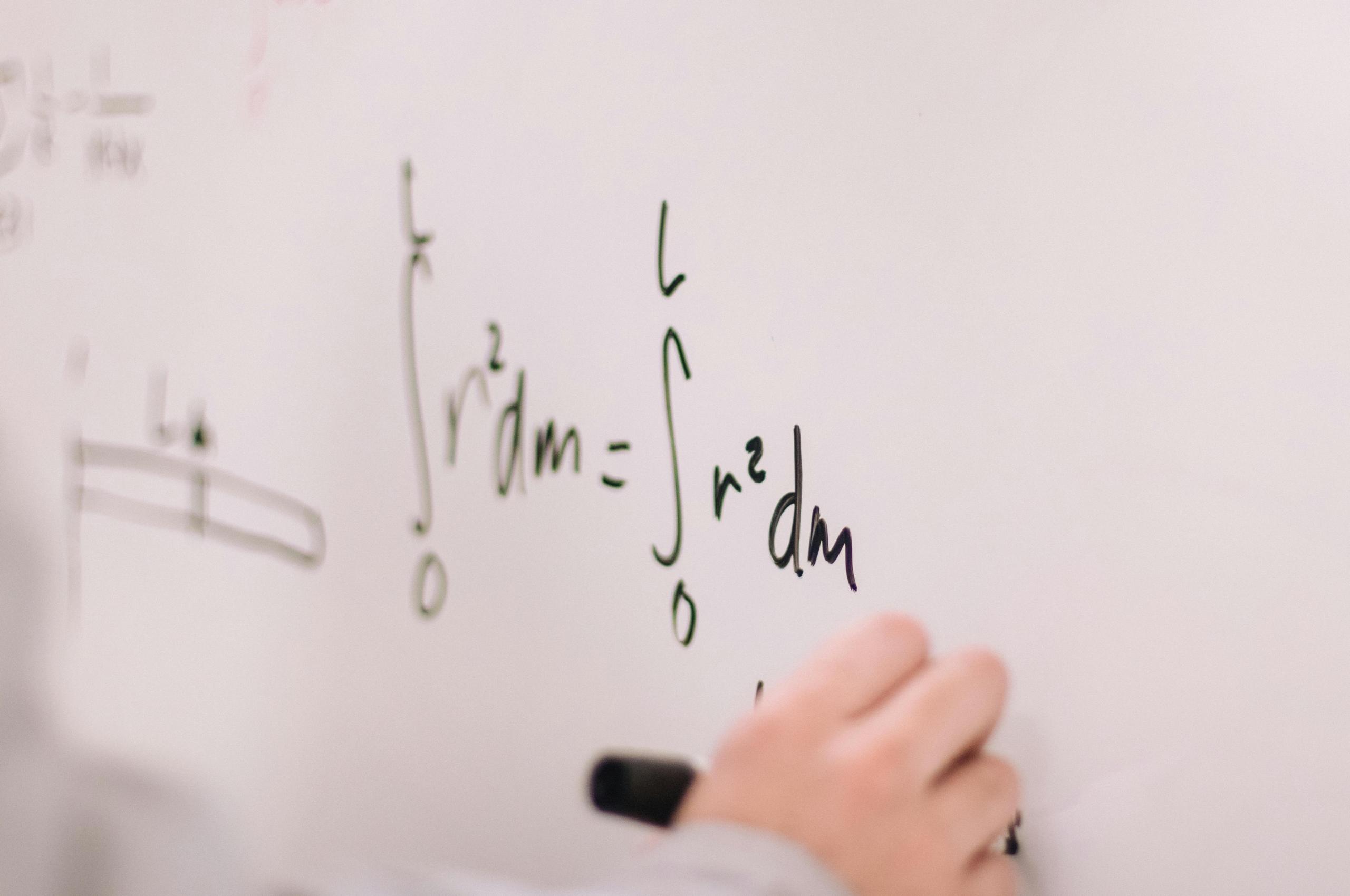 A physics equation written on a white board.