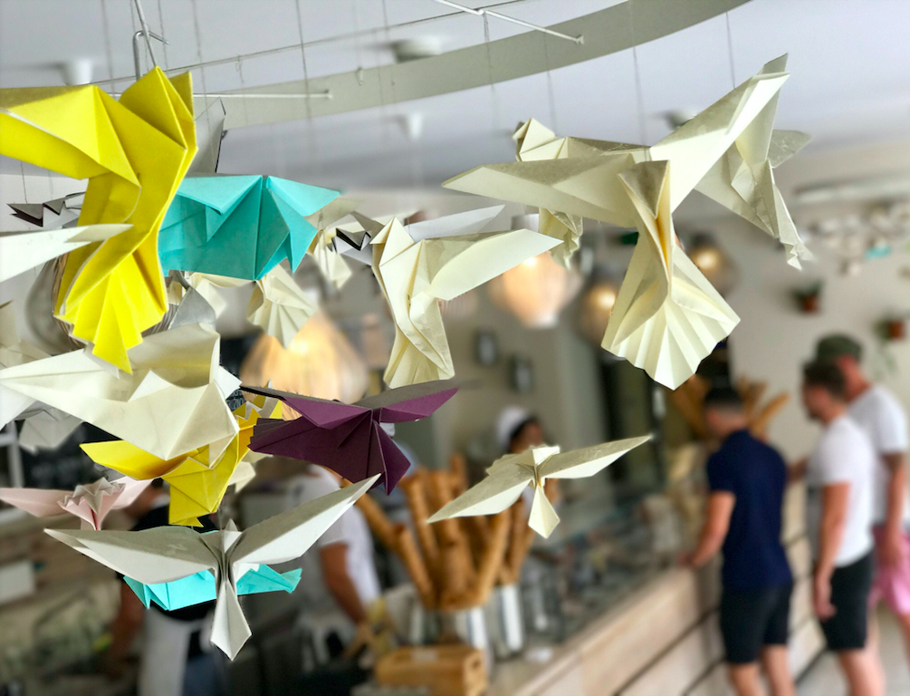 Origami birds in yellow, blue, and white hanging down from the ceiling.
