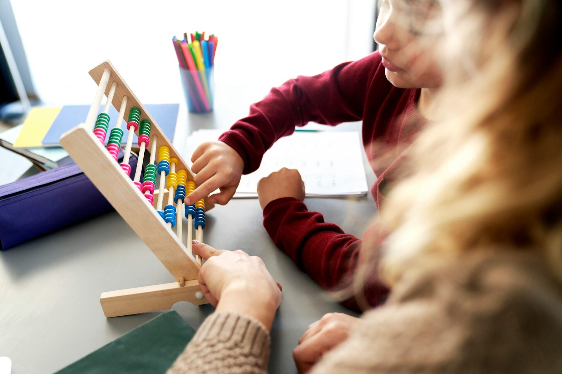 A kid and adult playing with an abacus.