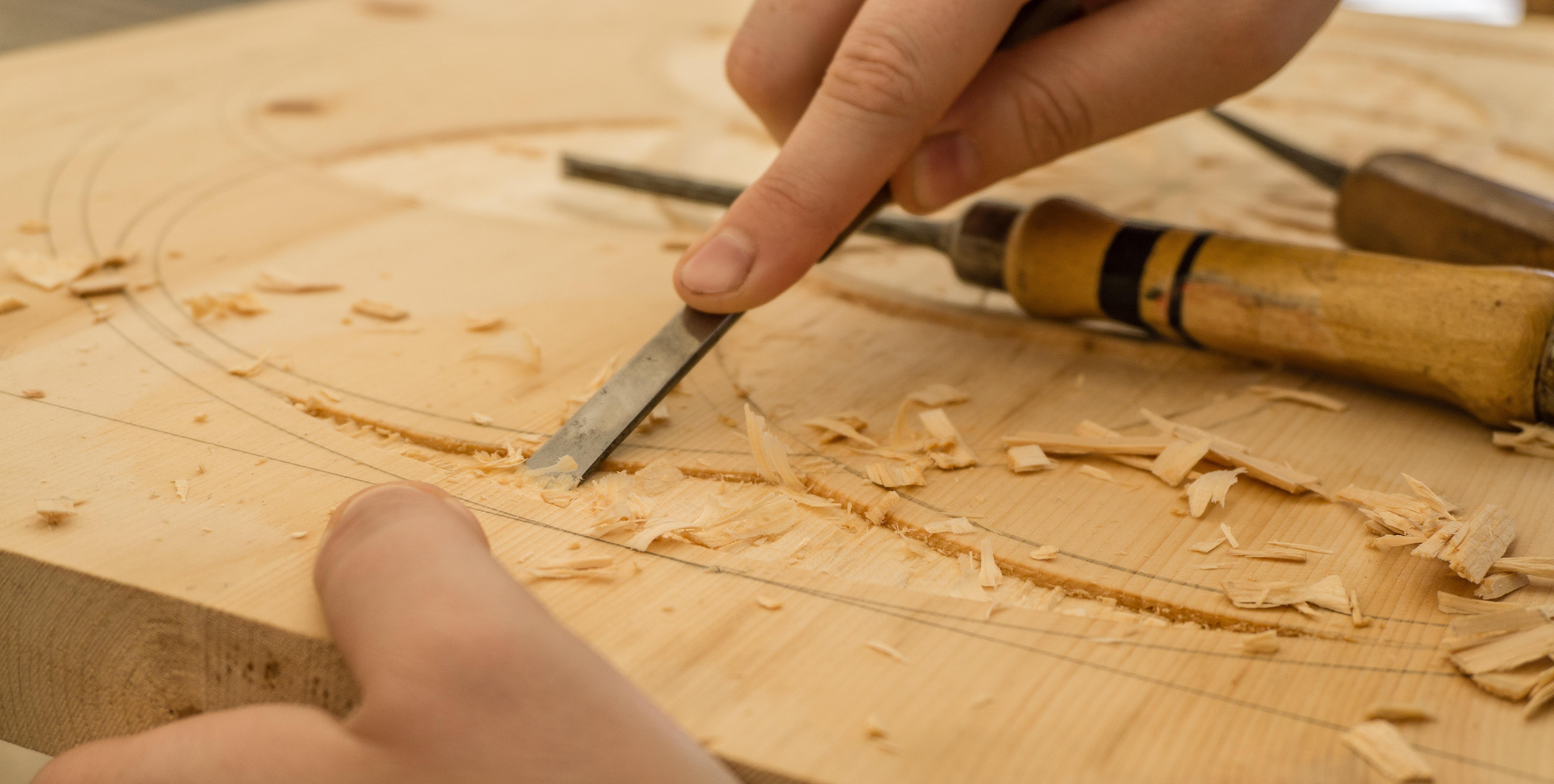 Image of a hands using a chisel to make a pattern in wood