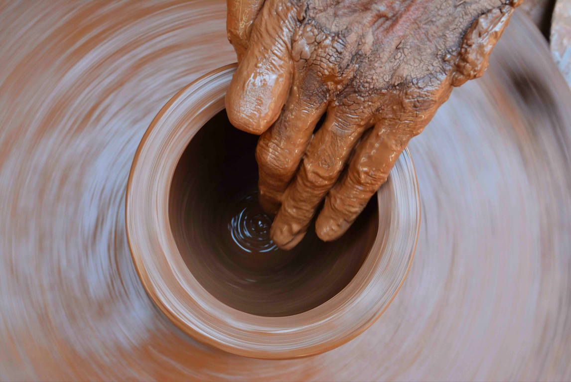 Hand hovering above a pottery wheel.