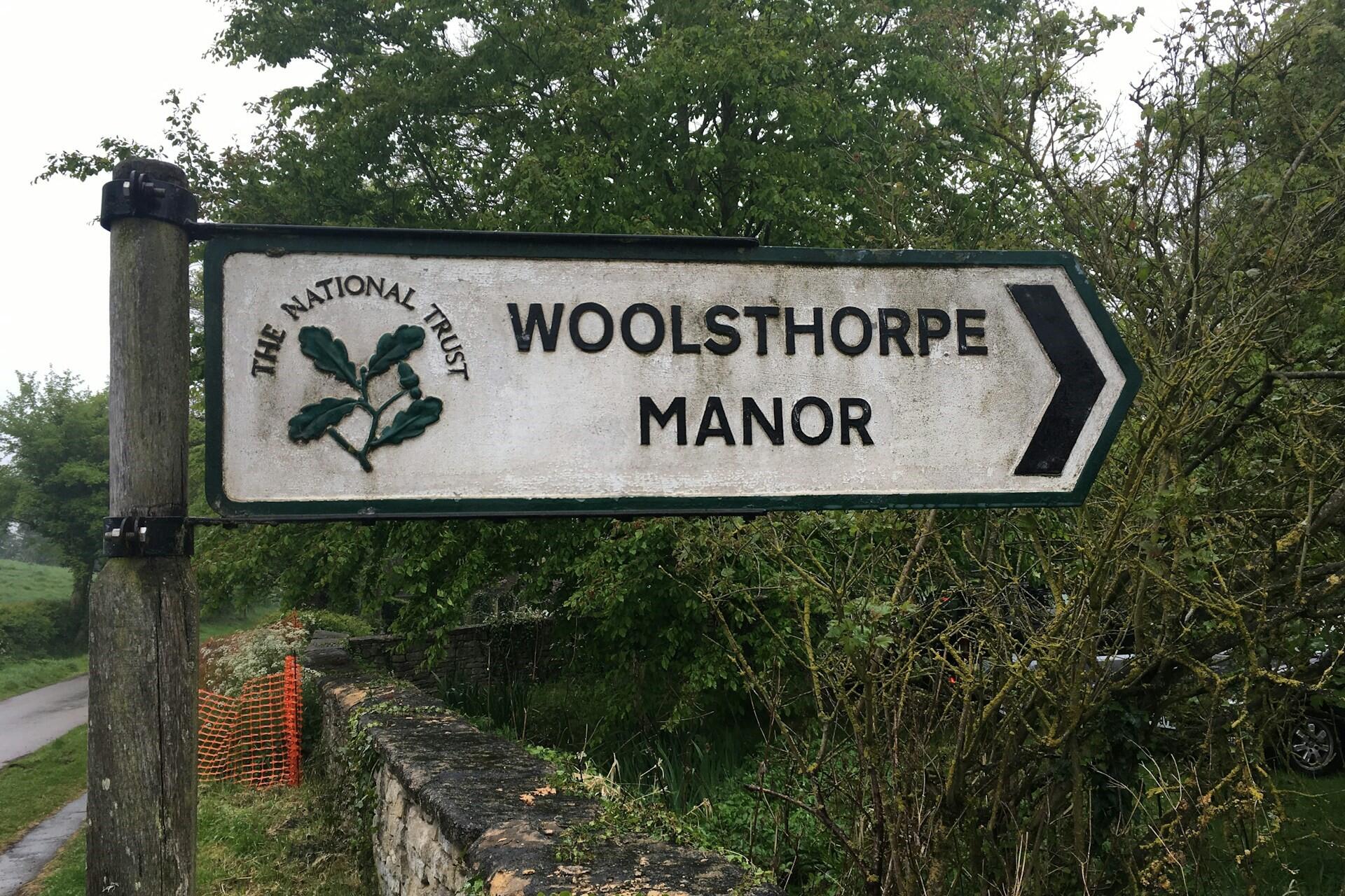 Road sign pointing to Woolsthorpe Manor surrounded by trees