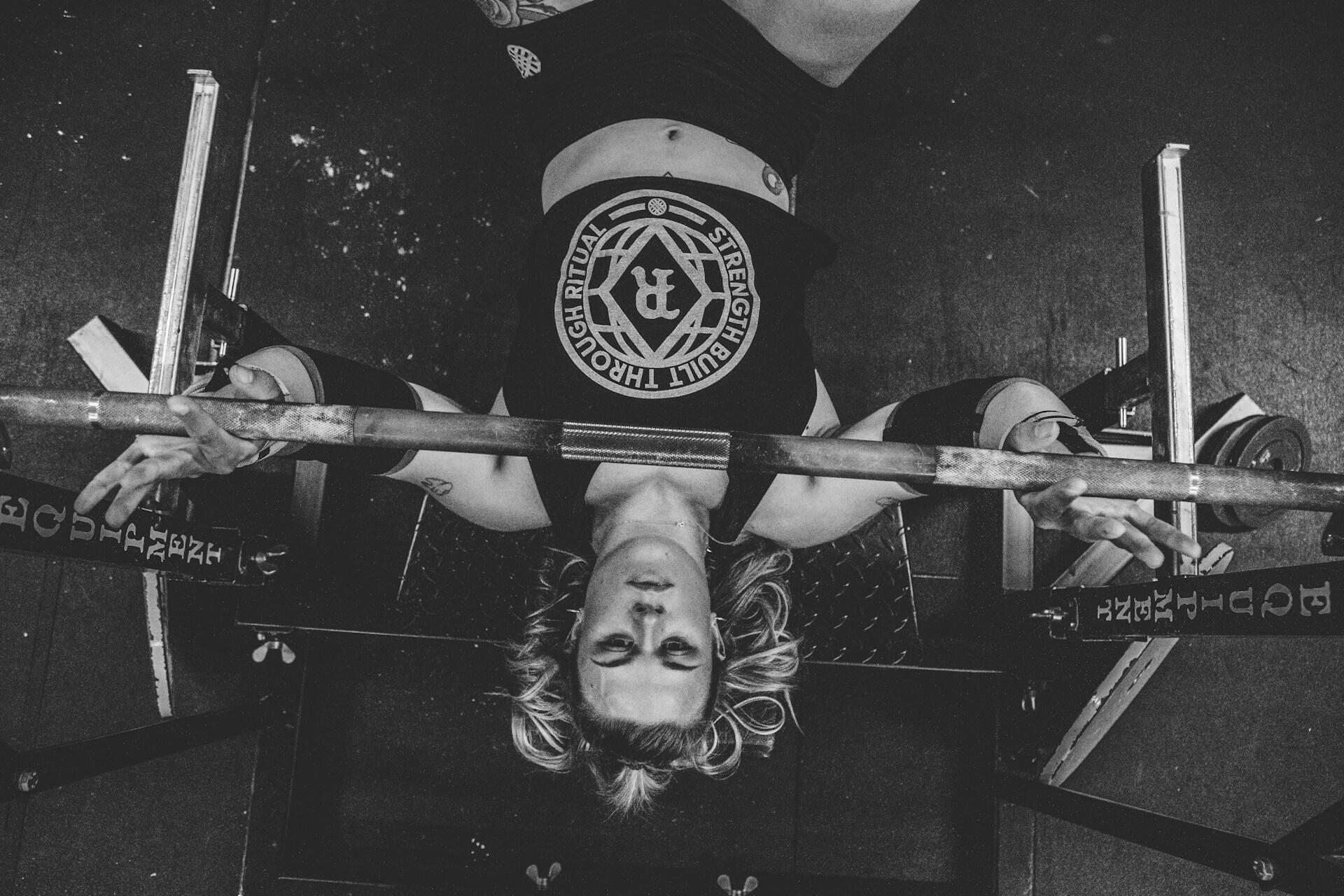 A black and white photo of a women bench pressing.