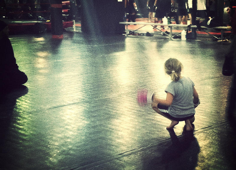 Girl kneeling wearing boxing gloves, sun on the boxing ring