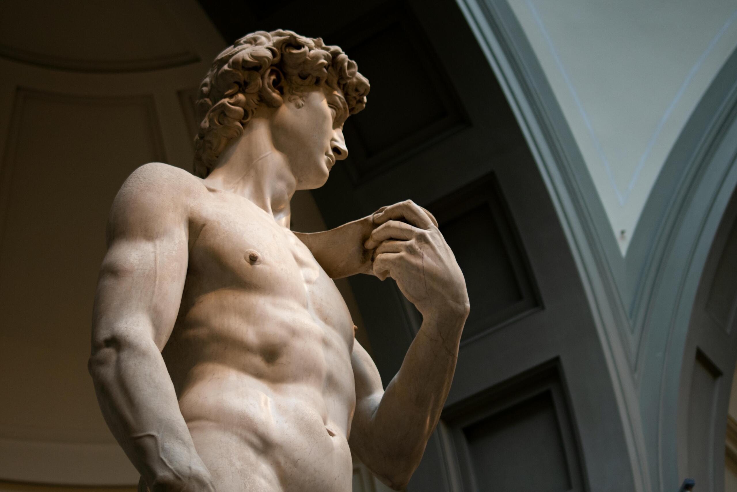 Low-angle view of a classical marble sculpture of a man against a clear sky.