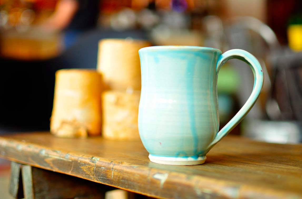 Light blue ceramic mug sitting on a wooden table.
