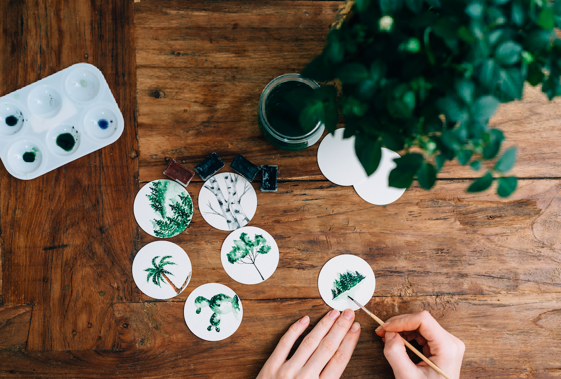 Painting watercolor trees on a wooden table.