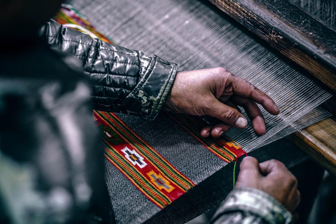 Person weaving colorful fabric.