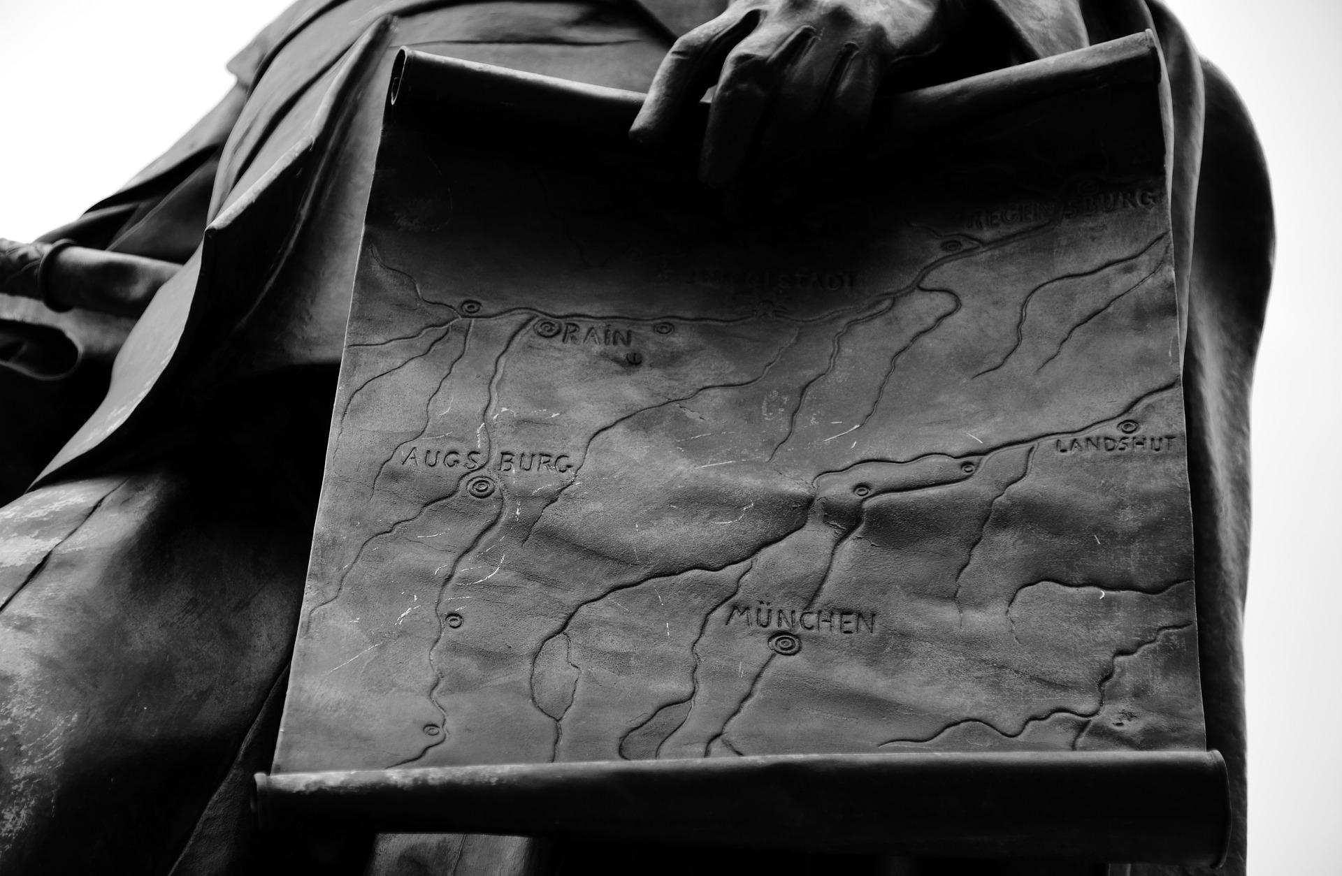 German statue holding an old stone German map