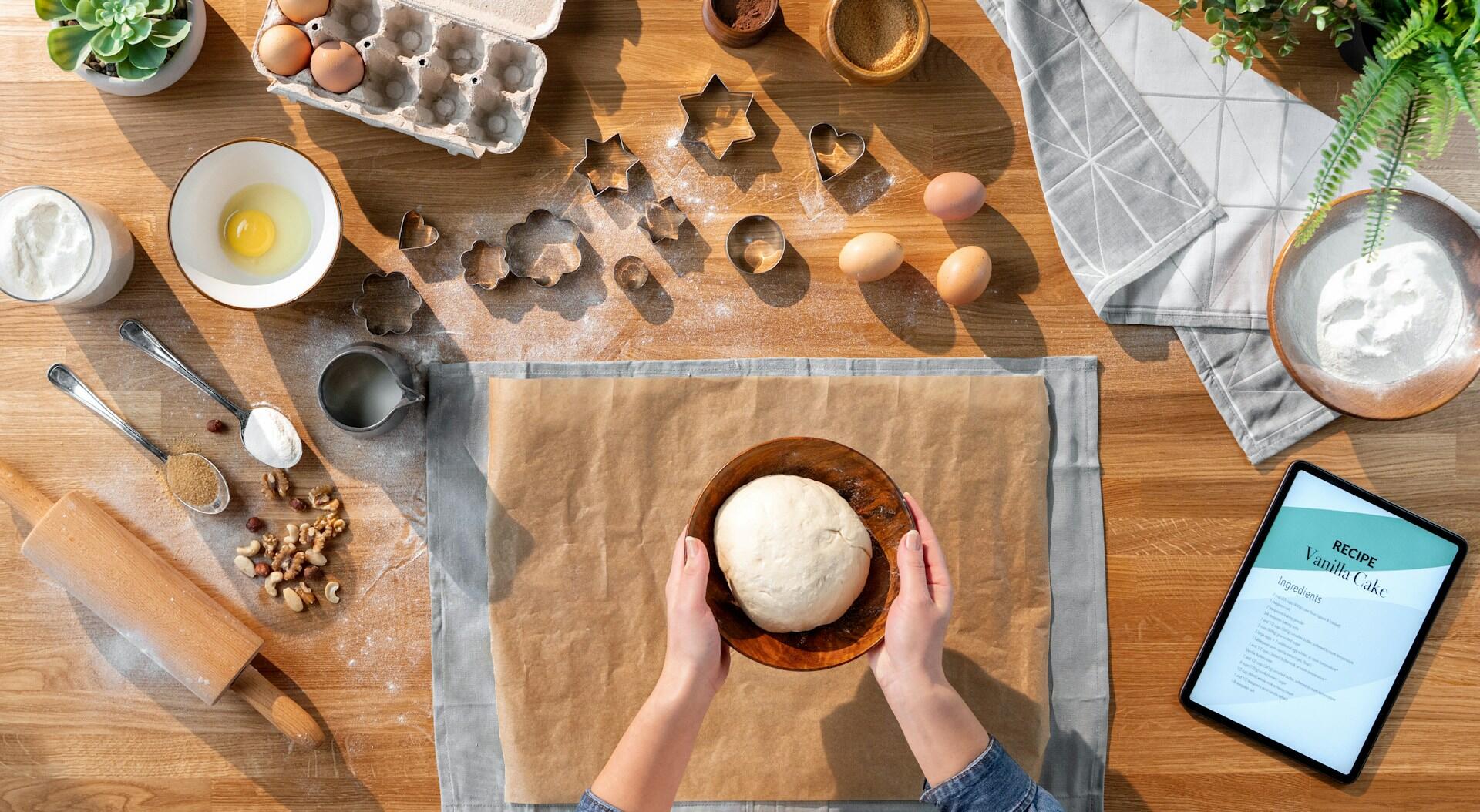 Someone baking in the kitchen with a vanilla cake recipe by them.