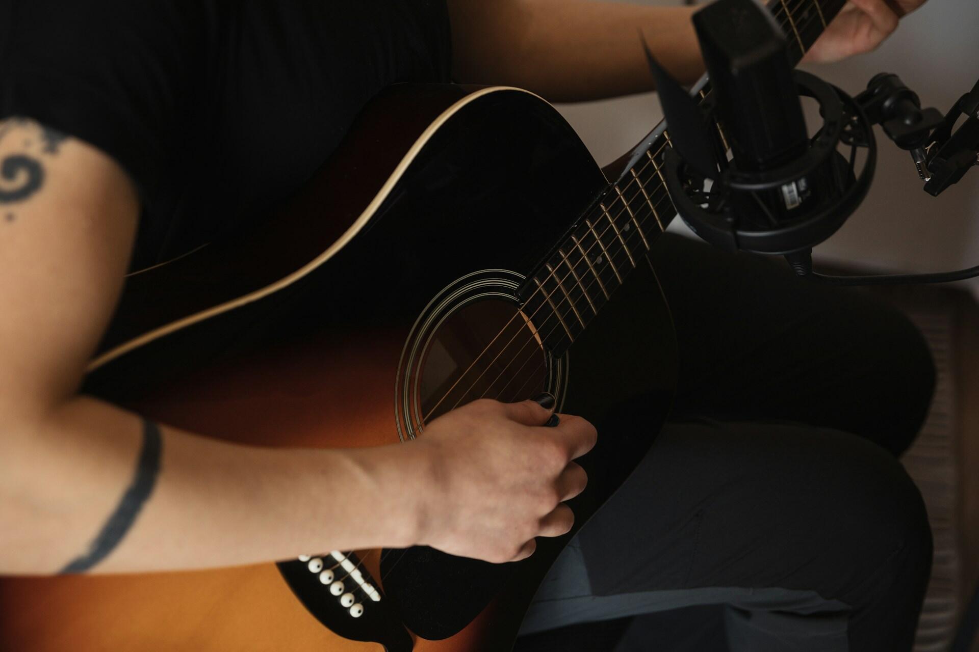 Someone with a tattoo playing the guitar.