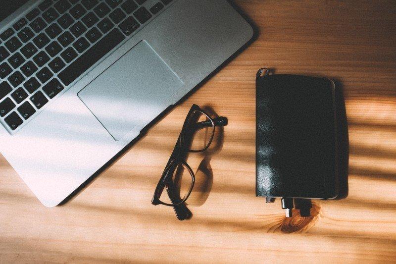 A computer with glasses and notepad. 