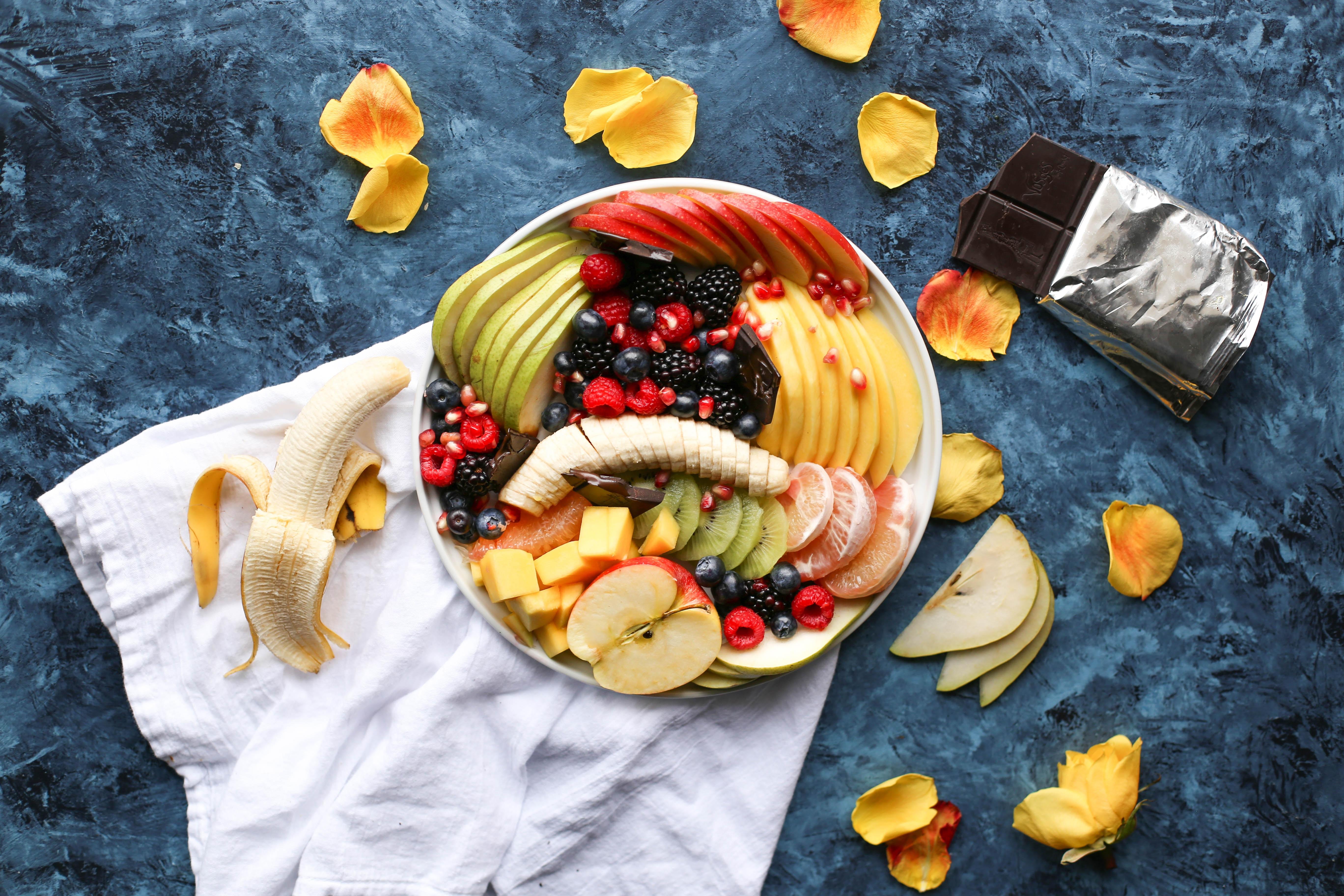 A variety of fruits sitting in a bowl on a marble countertop.