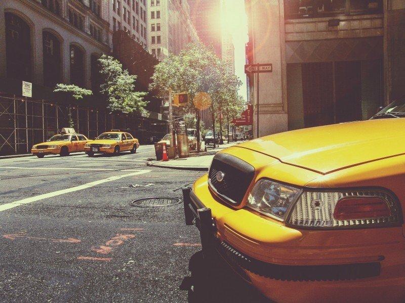 A yellow taxi turns on a busy New York street.