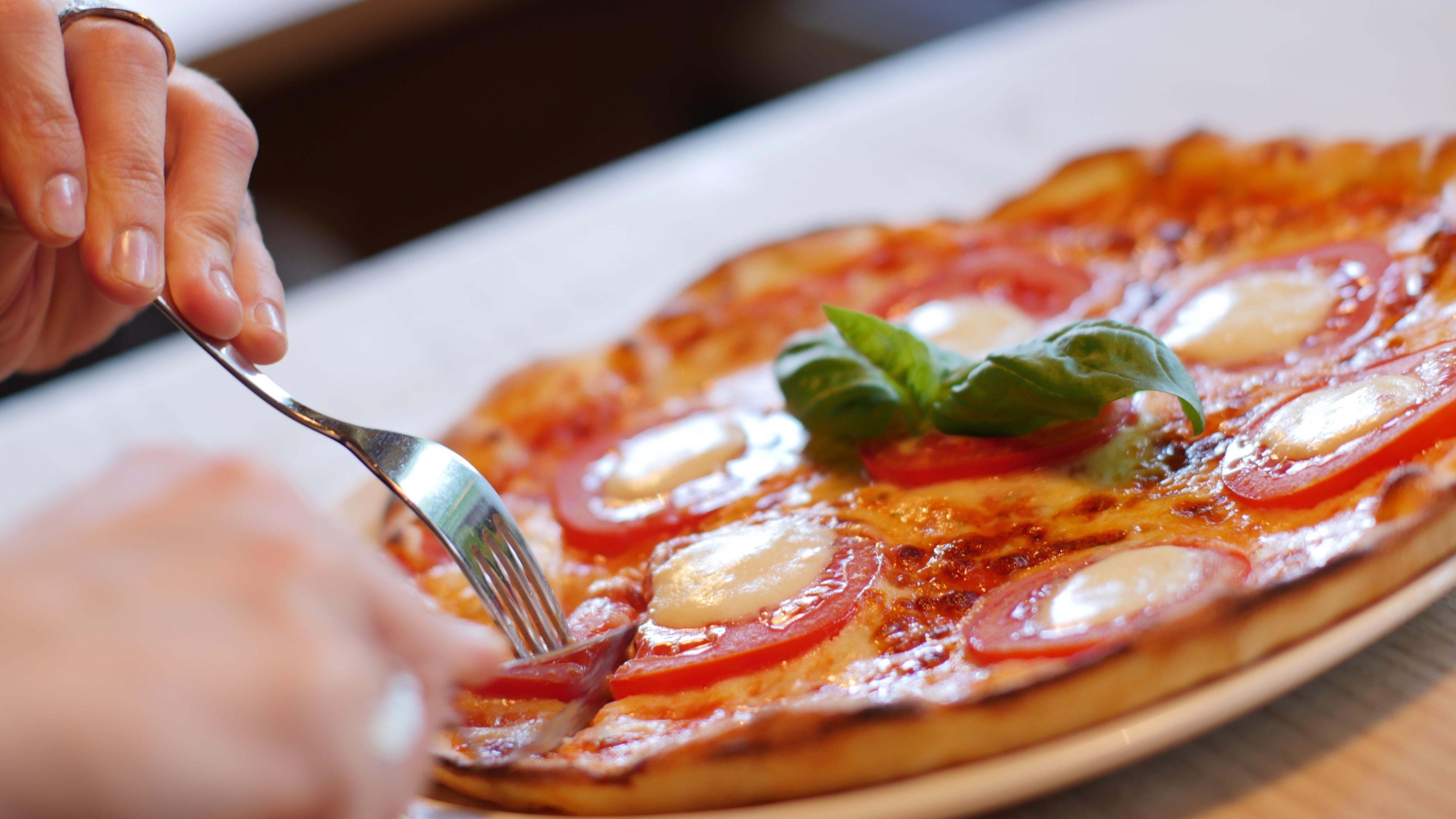 A pizza being sliced by a fork.