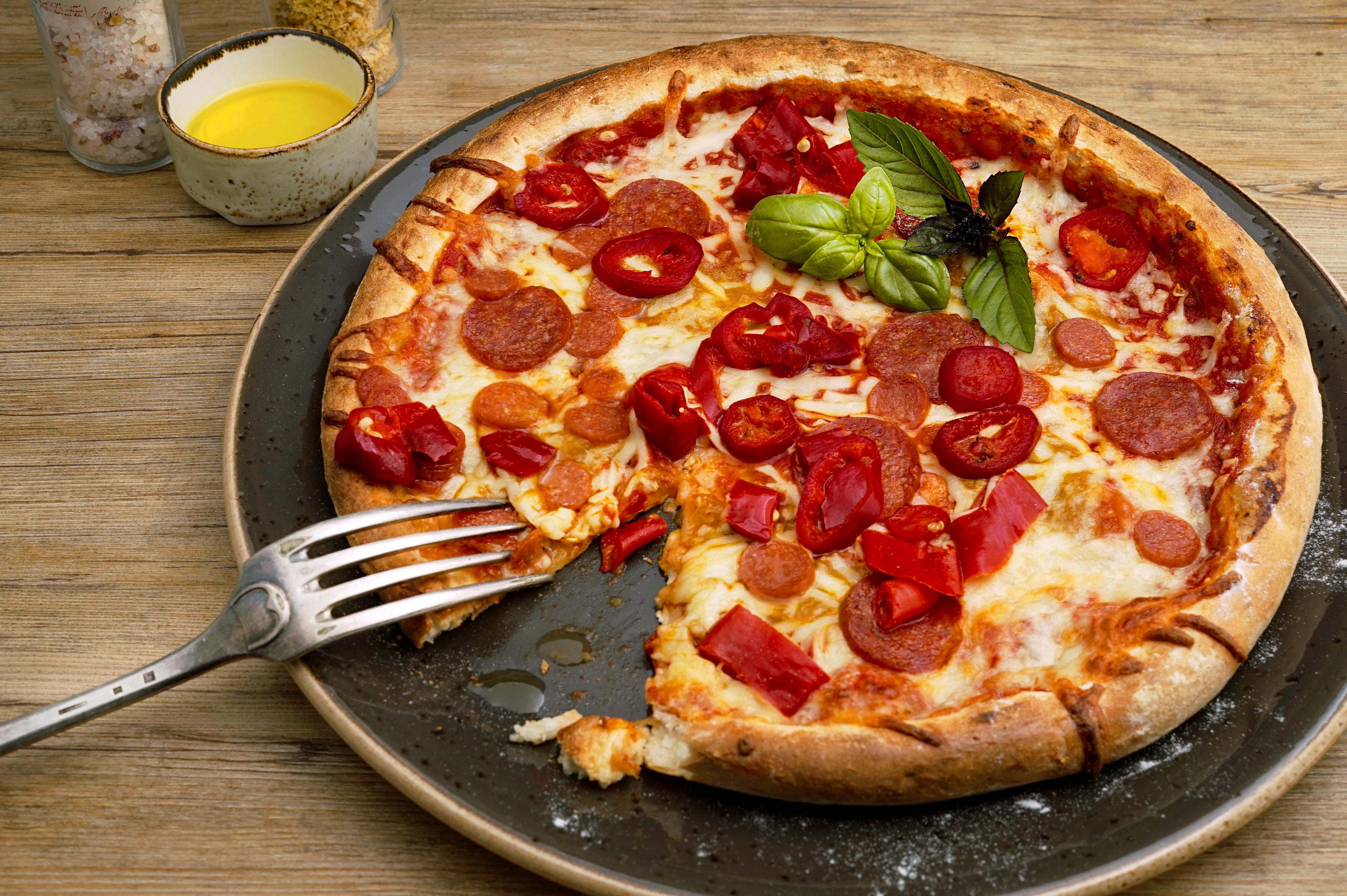 A round pizza being eaten with a fork.