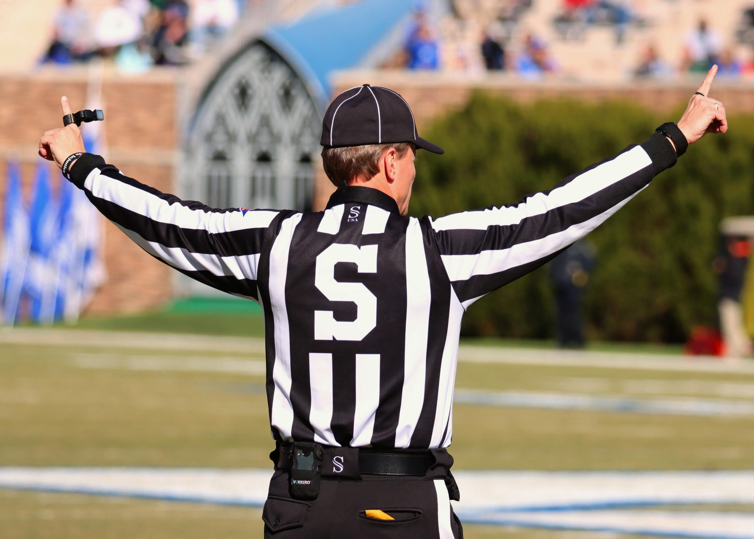 A sports referee with his arms stretched out.