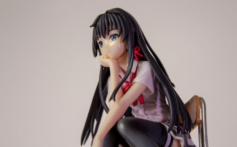 A black-haired female anime character sitting on a chair