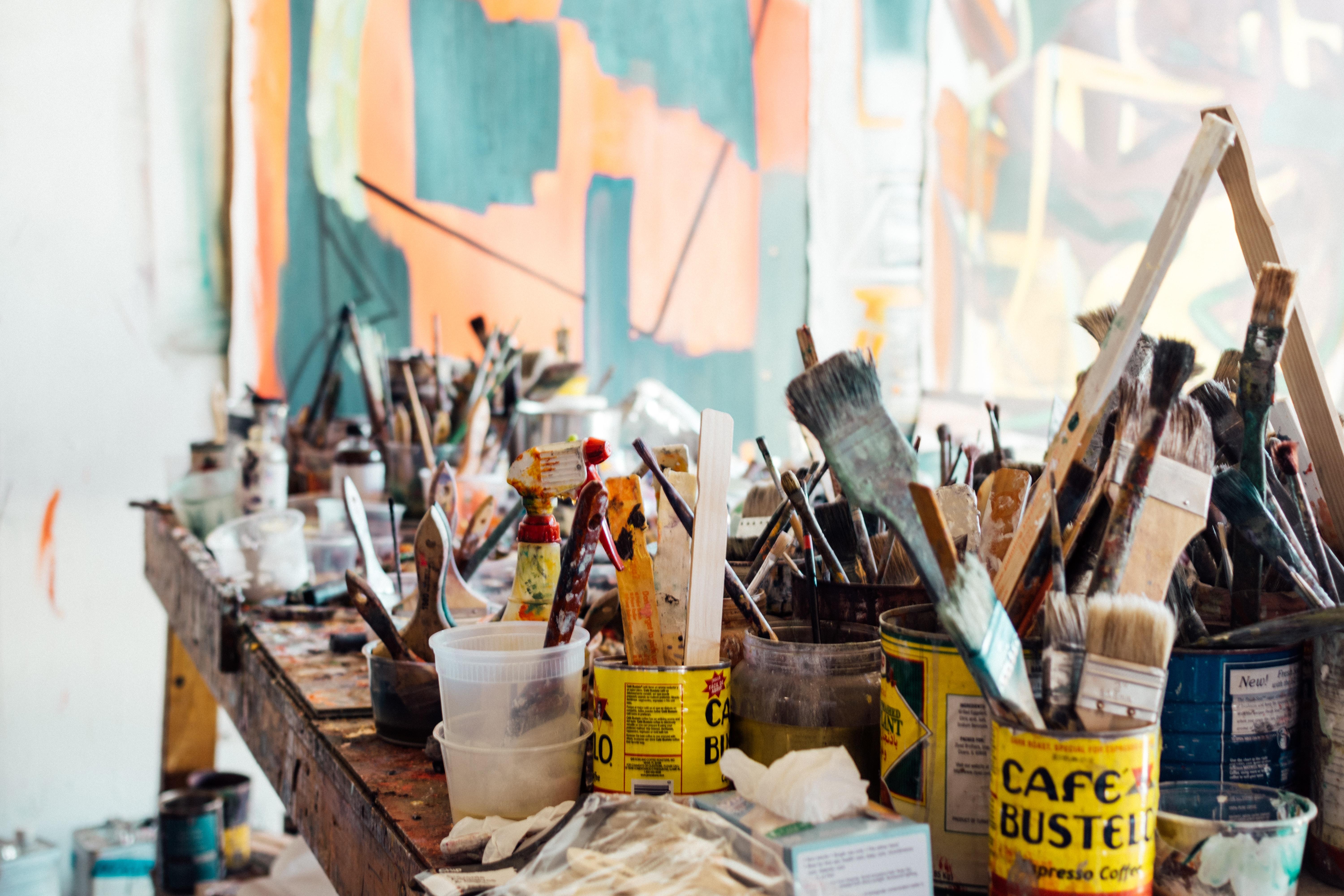 Cans of painting brushes sitting on a wooden table.