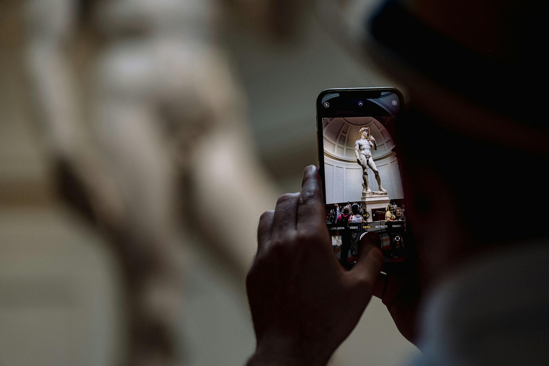 Person taking a picture of Michelangelo's David at the Galleria dell'Accademia in Florence.