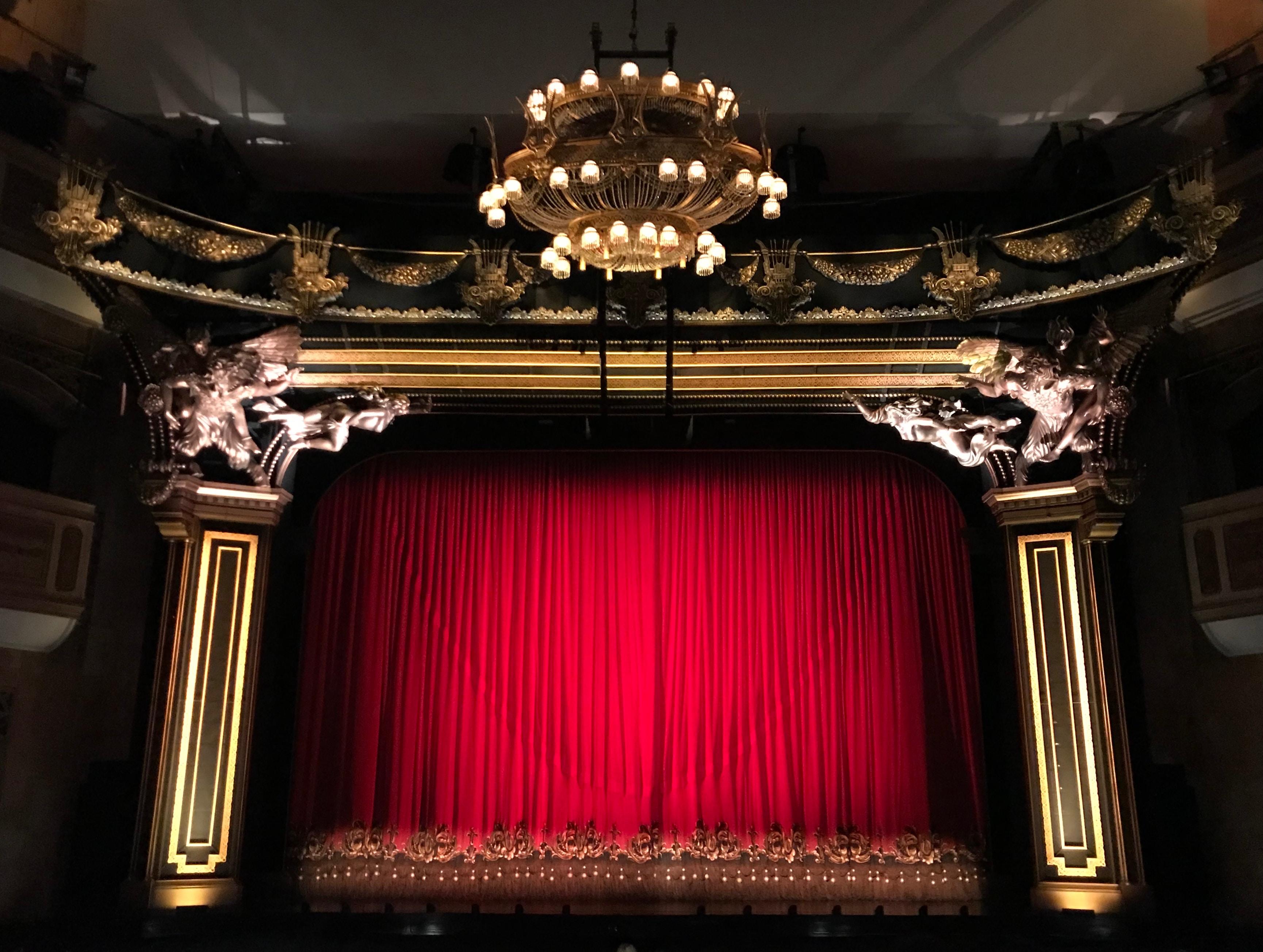 Red theatre curtains hanging down from a big stage.