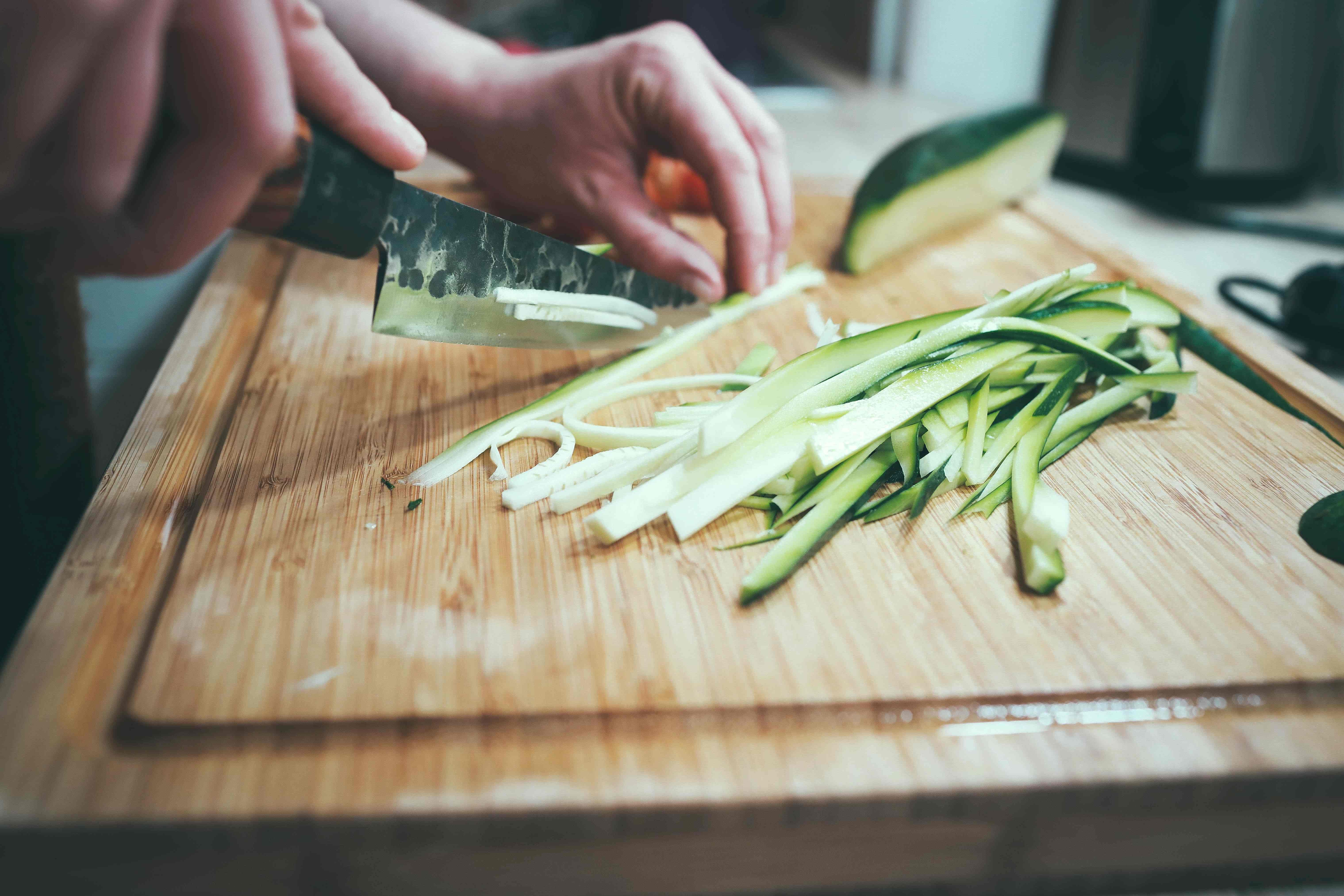 cucumber being sliced on a cutting board