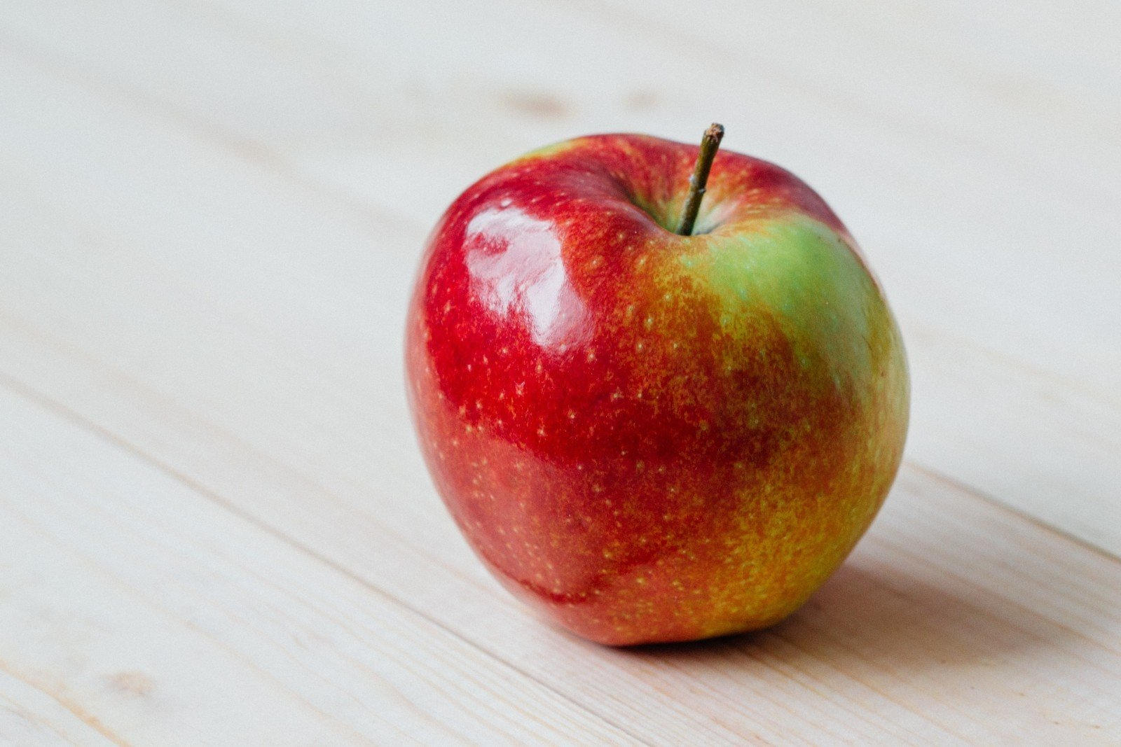 Single red apple on a wooden counter
