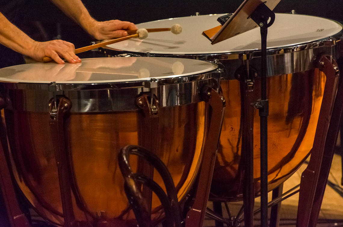 Person holding drum sticks playing bass drums.