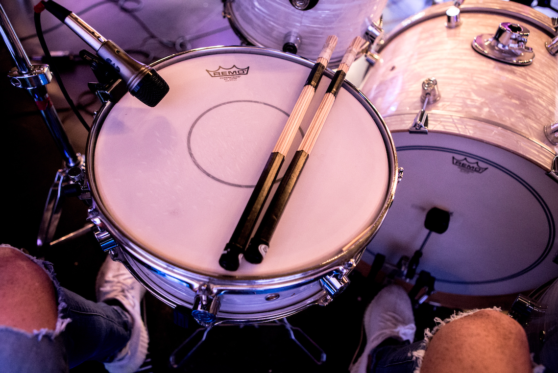 Top view of white drums with drumsticks on top.