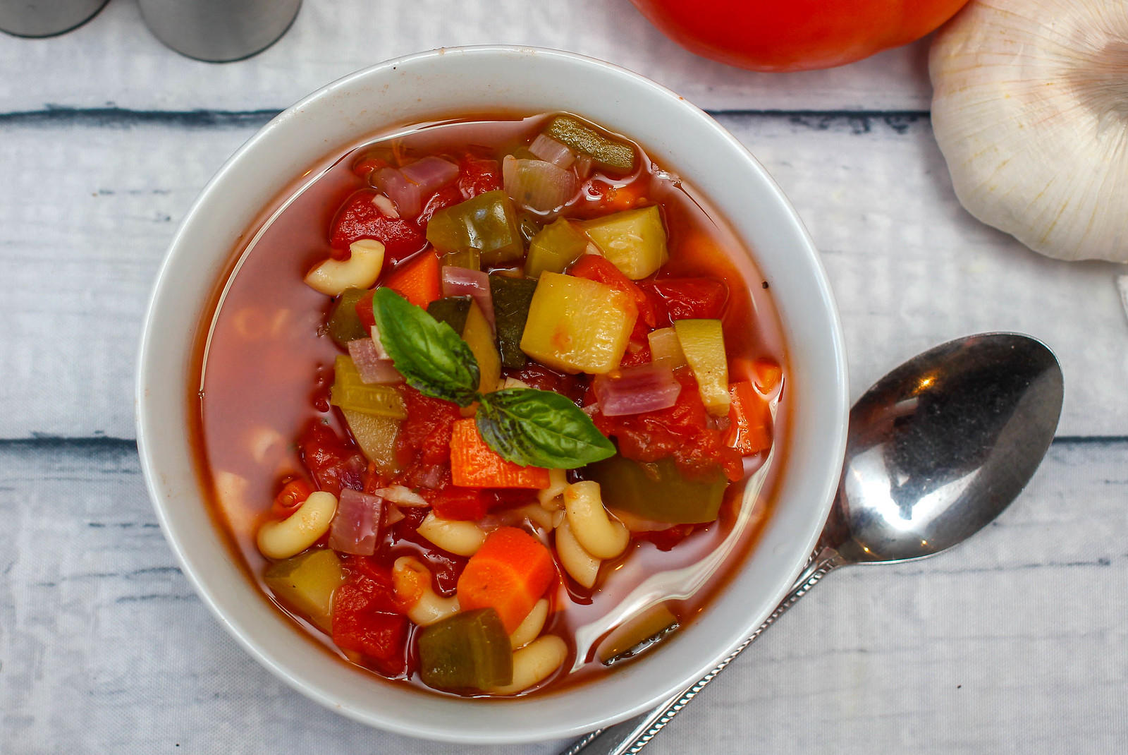minestrone soup served in a bowl with fresh basil