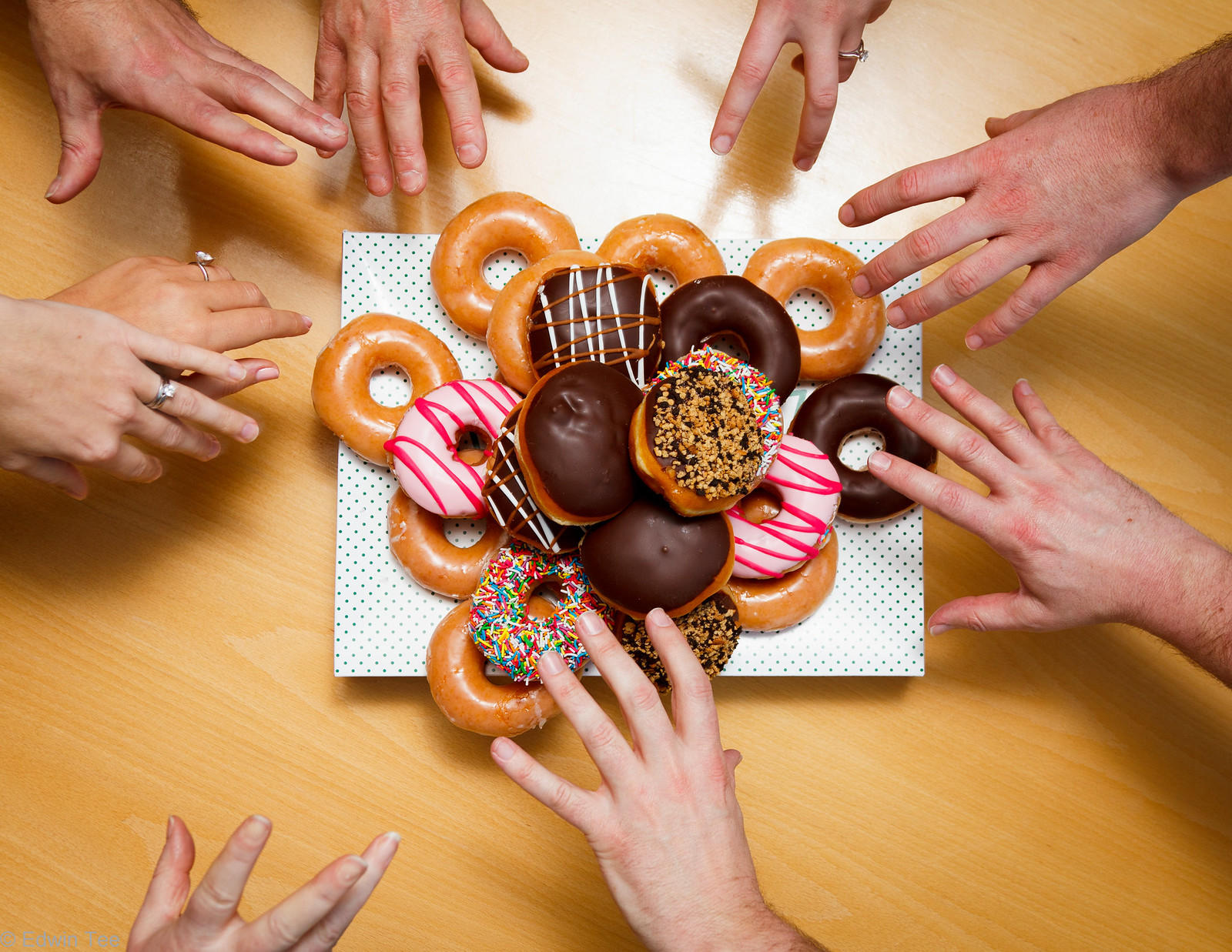 people reaching for fresh donuts