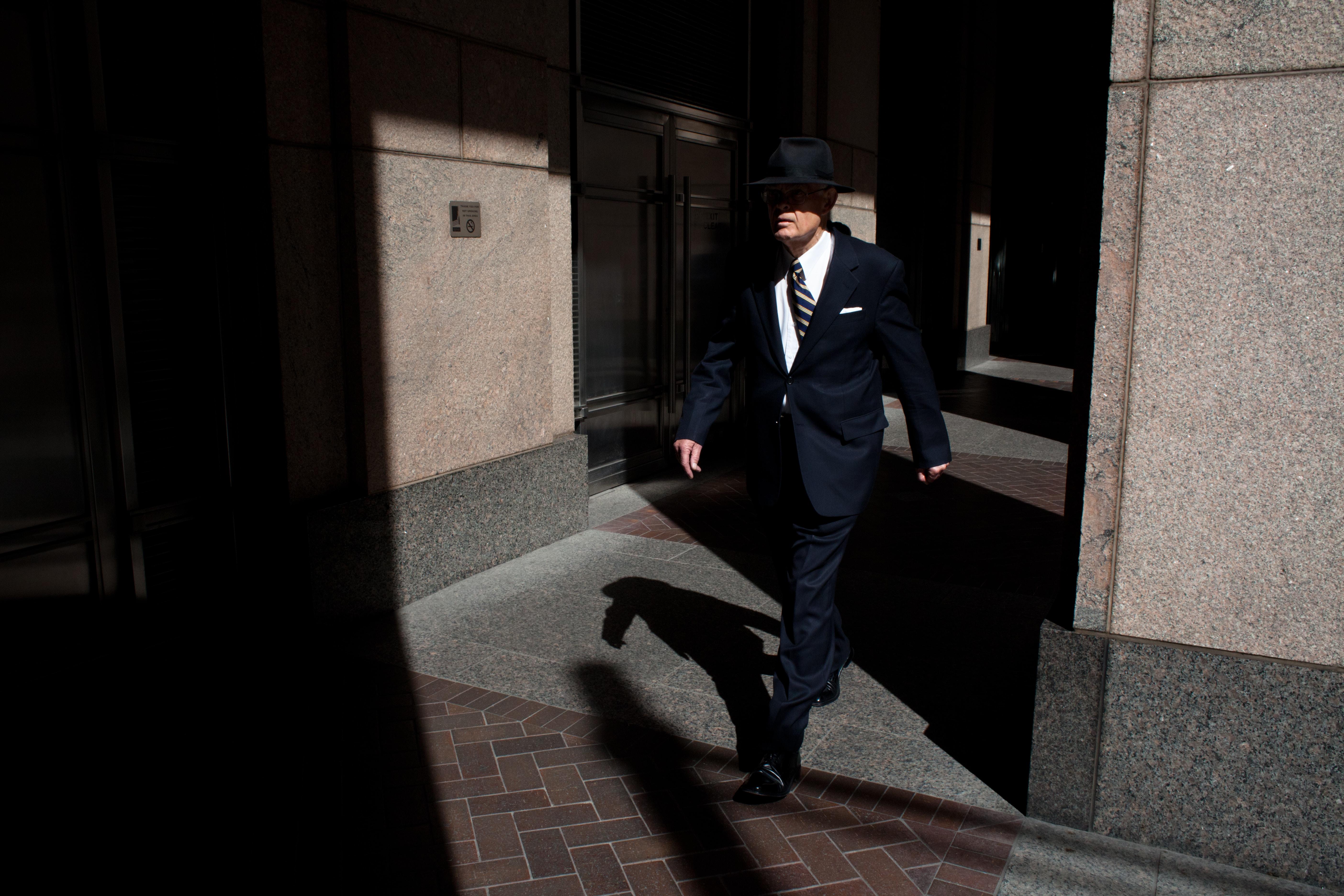 Man walking down a hallway in a black suit.