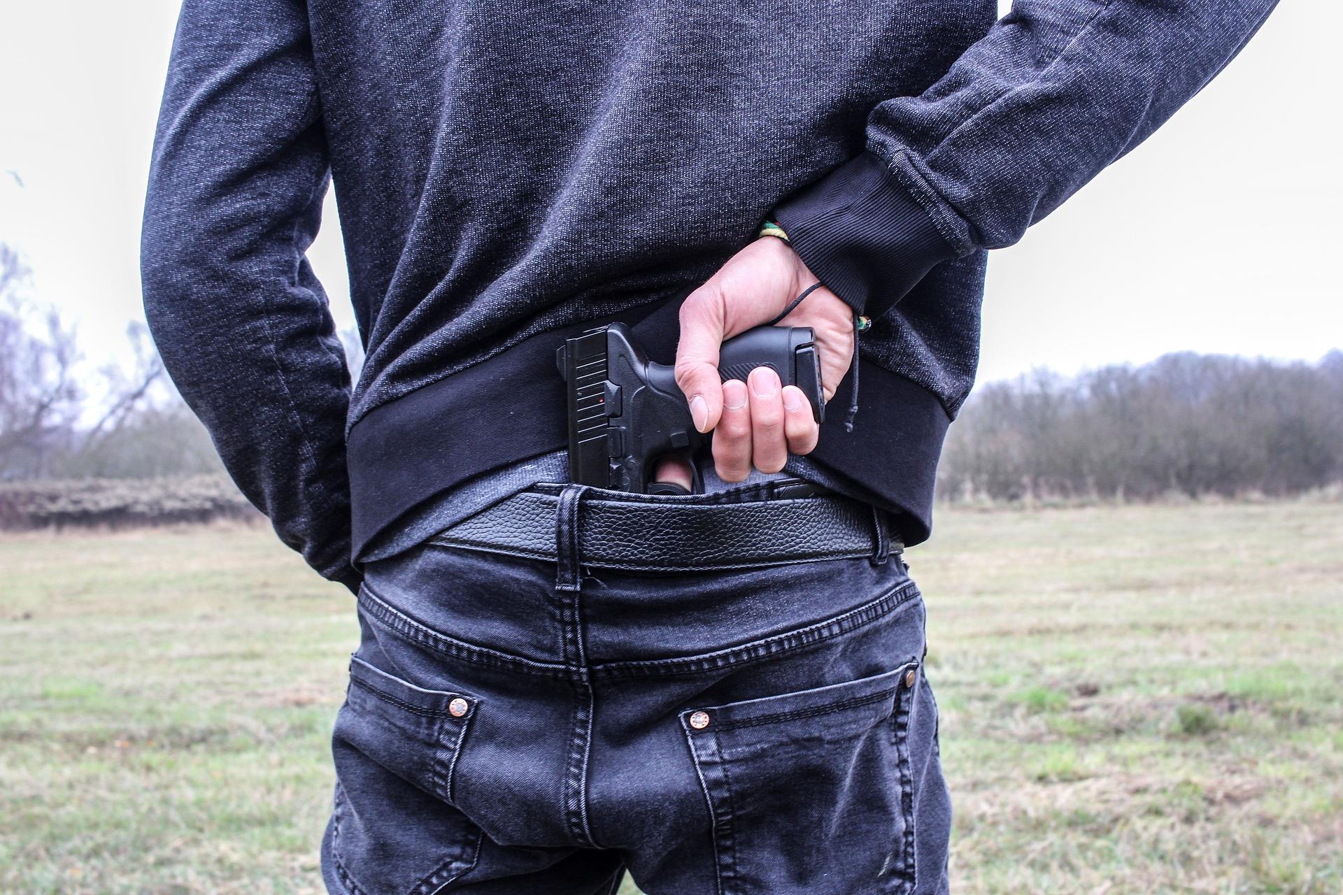 A criminal holding a gun at his back