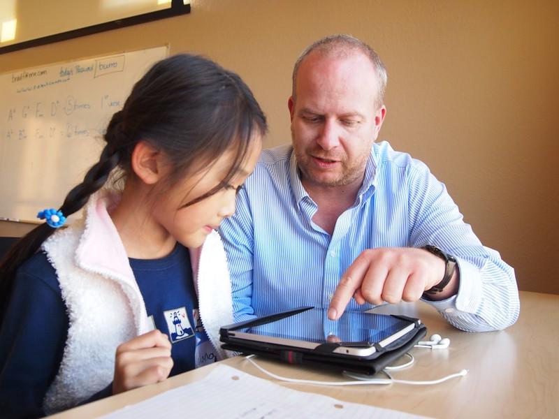 A tutor helping a child learn on a tablet