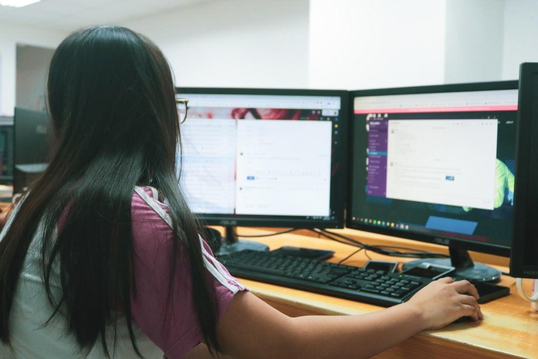 IT specialist working on desktop computer with two monitors