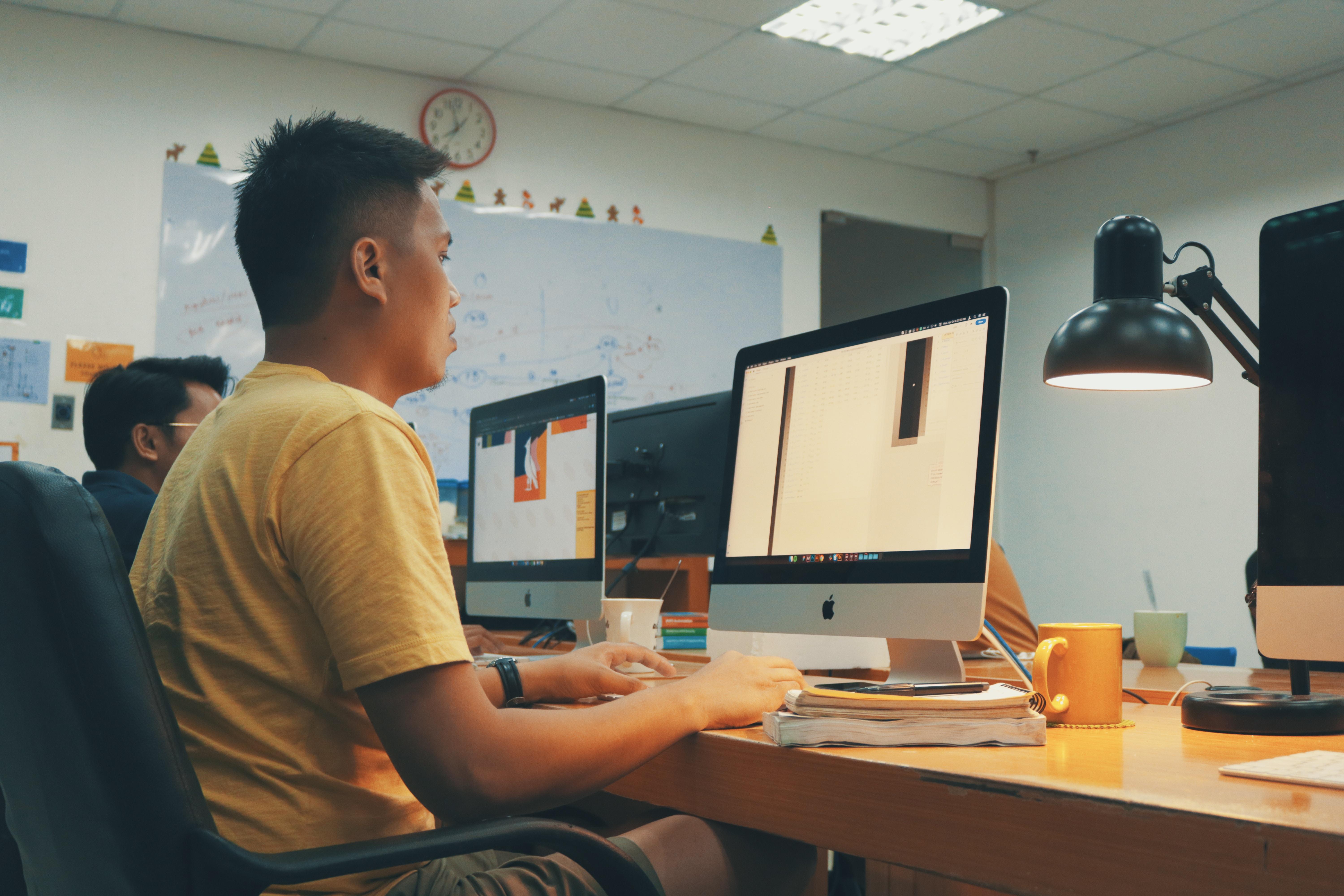 Man in classroom working at iMac.