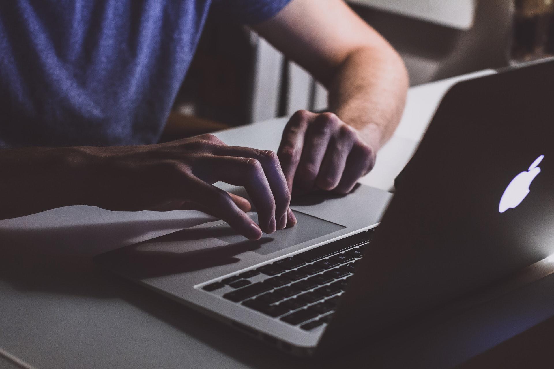 Man typing at laptop computer.