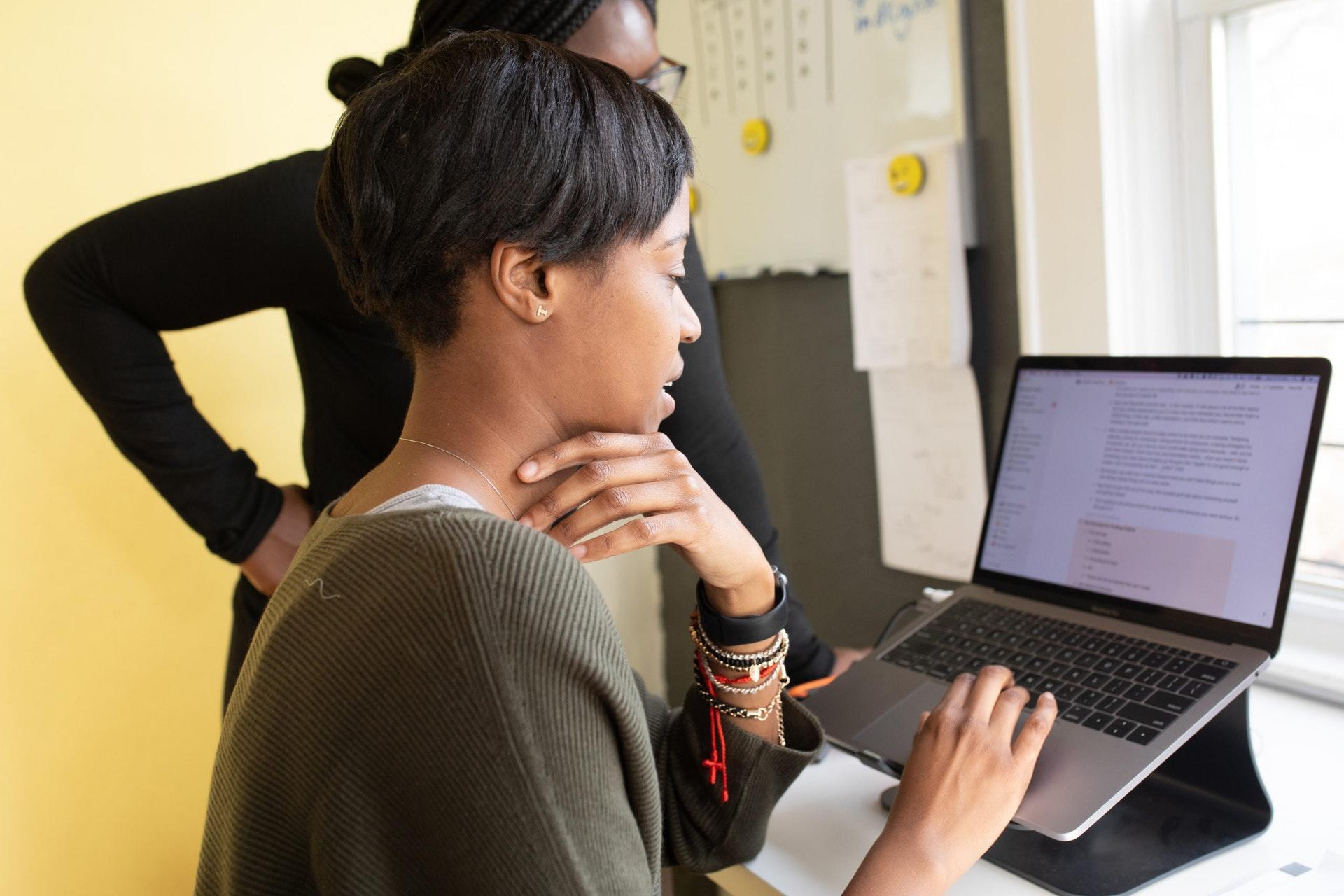 Two women looking at elevated laptop.