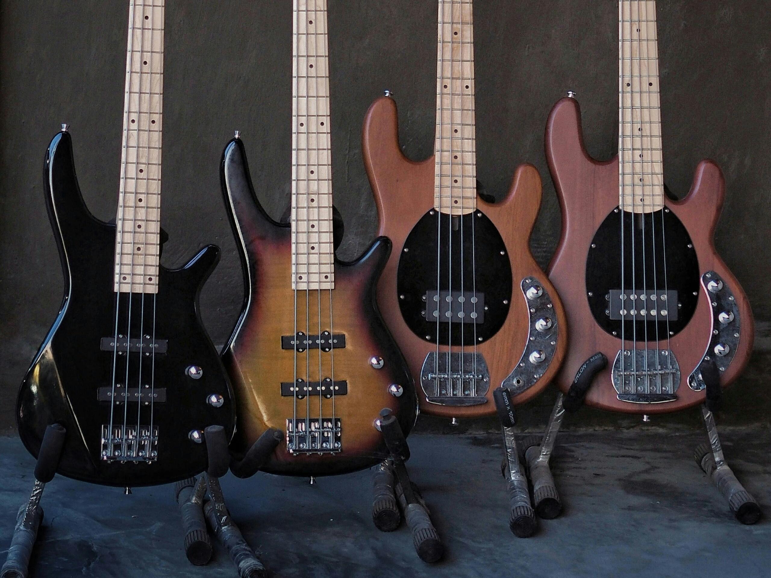 Four electric basses in their stands