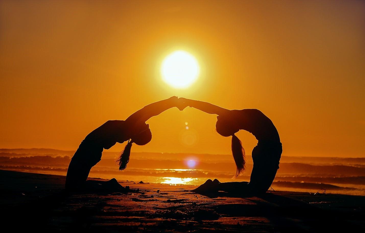 A mother and daughter practicing Yoga on the beach
